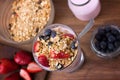 Glass with yogurt, cereals, strawberries and blueberries on wooden table - topview