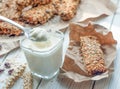 A glass of yogurt and handmade granola bars on a white wooden surface