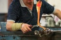 Glassblower at work, cutting liquid glass