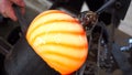 Glassblowing crafter rounds the hot-striped vase with wet wood tool at the end of the glass blowing pipe. Traditional glass art