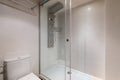 Glassed-in shower with modern controls next to the toilet in a compact bathroom. Concept of a bathroom in a five-star Royalty Free Stock Photo