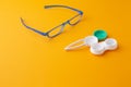 Glasses and accessories for contact lenses: a container for lenses and tweezers on a yellow background Royalty Free Stock Photo