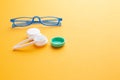 Glasses and accessories for contact lenses: a container for lenses and tweezers on a yellow background Royalty Free Stock Photo