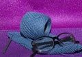 Glasses and accessories for knitting on a pink shiny background