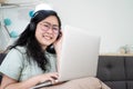 Glasses beautiful Asian woman is working on her laptop in the bedroom with a pastel green - brown color theme Royalty Free Stock Photo