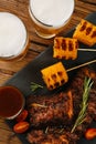 Glasses of beer, delicious grilled ribs, corn and sauces on wooden table, flat lay Royalty Free Stock Photo