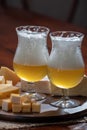Glass of Belgian light blond beer made in abbey and bowl with party mix nuts Royalty Free Stock Photo