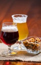 Glasses of Belgian yellow blond and dark brown beer made in abbey served in bar with party nuts