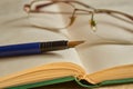 Glasses and a blue fountain pen lie on an open book Royalty Free Stock Photo