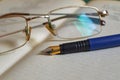 Glasses and a blue fountain pen lie on an open book Royalty Free Stock Photo