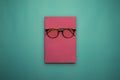 Glasses, book and stationery placed on blue background