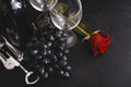 2 glasses, bottle of wine, dark grapes, corkscrew, red rose on black background Royalty Free Stock Photo