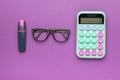 Glasses, calculator and marker on a purple background Royalty Free Stock Photo