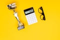 Glasses, calculator and winner cup on a clean yellow table background Royalty Free Stock Photo