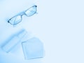 Glasses care product. Glasses, spray, napkin for glasses on light background. Blue monochrome background. Ophthalmology