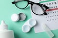 Glasses, case for contact lenses and eye test chart on background, top view Royalty Free Stock Photo