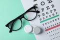 Glasses, case for contact lenses and eye test chart on mint background Royalty Free Stock Photo