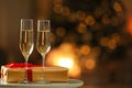 Glasses with champagne and gift on table in room, bokeh effect. Space for text Royalty Free Stock Photo