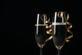 Glasses of champagne with curly ribbons on black background