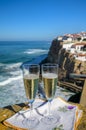 Glasses of champagne sparkling wine and view on white houses of picturesque village Azenhas do mar, Lisbon area, Portugal Royalty Free Stock Photo