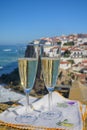 Glasses of champagne sparkling wine and view on white houses of picturesque village Azenhas do mar, Lisbon area, Portugal Royalty Free Stock Photo