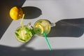 Glasses with chilled lemon mojito with green mint leaves and pieces of sour yellow lemon on a gray background. Top view