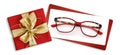 Glasses christmas gift card, red box with glittering golden ribbon bow, white ticket and eyewear isolated on white background,