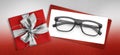 Glasses christmas gift card, red box with glittering silver ribbon bow, white ticket and black eyewear isolated on white Royalty Free Stock Photo