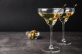 Glasses of Classic Dry Martini with olives on grey table against black background. Space Royalty Free Stock Photo