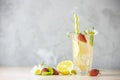 Glasses of cold icy refreshing drink with lemon and strawberry served on light pink table.  Fresh cocktail drinks with ice fruit, Royalty Free Stock Photo