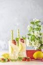 Glasses of cold icy refreshing drink with lemon and strawberry served on light pink table. Fresh cocktail drinks with ice fruit Royalty Free Stock Photo