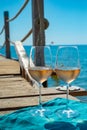 Glasses of cold rose wine from Provence served outdoor on wooden yacht pier with view on blue water and white sandy beach Plage de