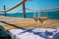 Glasses of cold rose wine from Provence served outdoor on wooden yacht pier with view on blue water and white sandy beach Plage de