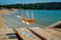 Glasses of cold rose wine from Provence served outdoor on wooden yacht pier with view on blue water and white sandy beach Plage de