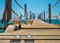 Glasses of cold rose wine from Provence served outdoor on wooden yacht pier with view on blue water and white sandy beach Plage de