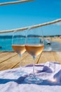 Glasses of cold rose wine from Provence served outdoor on wooden yacht pier with view on blue water and white sandy beach Plage de