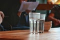 2 Glasses of cold water with ceramic cups in coffee shop on wooden table background