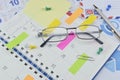 Glasses with colorful sticky notes and pen on diary page Royalty Free Stock Photo