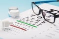 Glasses with Contact Lenses, drops and an Optometrist`s Eye Test Chart On a Blue Background Royalty Free Stock Photo