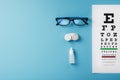 Glasses with Contact Lenses, drops and an Optometrist`s Eye Test Chart On a Blue Background Royalty Free Stock Photo