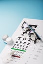 Glasses with Contact Lenses, drops and an Optometrist`s Eye Test Chart On a Blue Background Royalty Free Stock Photo