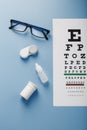 Glasses with Contact Lenses, drops and an Optometrist`s Eye Test Chart On a Blue Background Royalty Free Stock Photo
