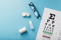 Glasses with Contact Lenses, drops and an Optometrist`s Eye Test Chart On a Blue Background Royalty Free Stock Photo