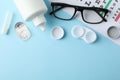 Glasses, contact lenses and eye test chart on background, top view