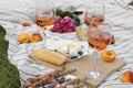 Glasses of delicious rose wine, flowers and food on picnic blanket outdoors Royalty Free Stock Photo