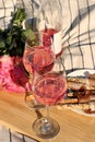 Glasses of delicious rose wine, flowers and food on white picnic blanket Royalty Free Stock Photo