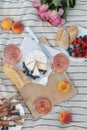 Glasses of delicious rose wine, flowers and food on white picnic blanket, flat lay Royalty Free Stock Photo