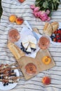 Glasses of delicious rose wine, flowers and food on white picnic blanket, flat lay Royalty Free Stock Photo