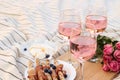 Glasses of delicious rose wine, flowers and food on picnic blanket Royalty Free Stock Photo