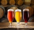 Glasses of different chilled beer and wooden beer casks on the background